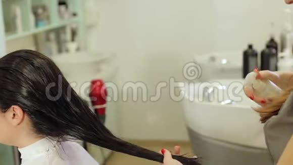 特写美发师溅湿发女护油头发护理视频的预览图