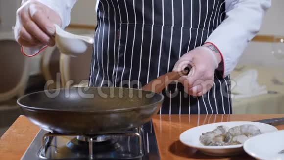 餐厅烹饪厨师戴手套将橄榄油倒入平底锅中炸花式虎虾慢动作视频的预览图