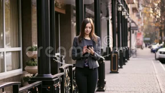 漂亮的女商人在街上使用智能手机应用程序上网慢动作视频的预览图