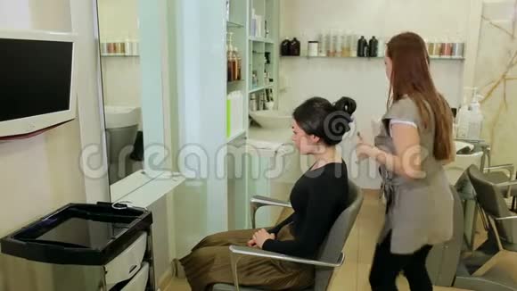 女理发师正在一家美发店里给一个年轻女孩的脖子上修领子视频的预览图