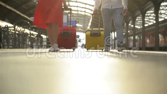 脚在站台上行走乘客带着西装革履年轻夫妇沿着站台走到火车上视频的预览图