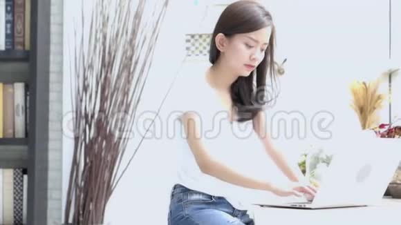 美丽的年轻自由职业亚洲女性微笑着工作在手提电脑和交谈客户电话视频的预览图