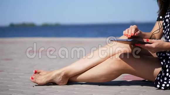 特写女孩在写字板上工作女性的手腿用鲜红的指甲指甲修脚在沙滩上在炎热的天气视频的预览图