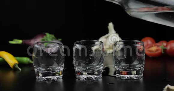 把酒精伏特加倒入三杯中蔬菜背景视频的预览图