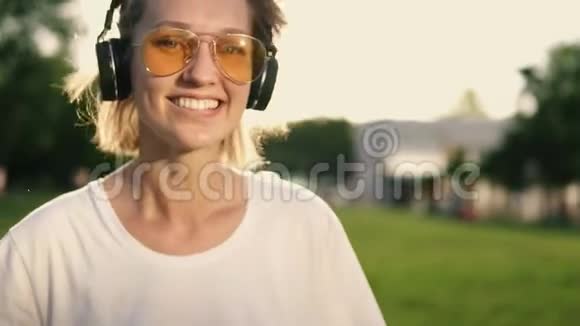 可爱的白种人女孩在户外玩得很开心戴着白色T恤对着镜头微笑戴着耳机视频的预览图
