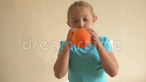穿蓝色t恤的快乐女孩在家里的浴室里充气了一个明亮的橙色球浅淡的焦点视频的预览图