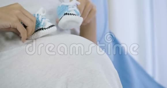 孕妇在肚子上为胎儿在床上玩小鞋视频的预览图