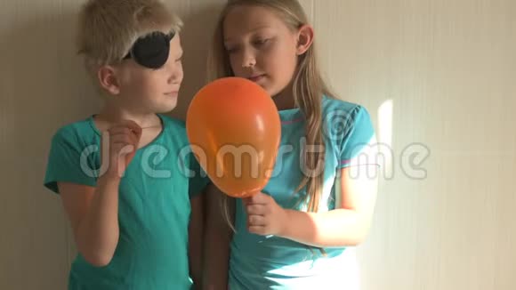 穿着蓝色T恤的快乐女孩在家里的浴室里吹着明亮的气球带针的金发男孩穿着气球浅视频的预览图
