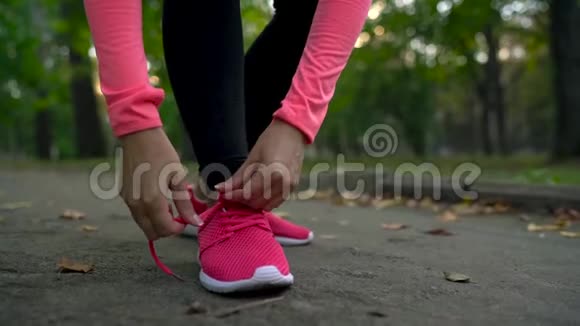 在日落时分女人系鞋带穿过一个秋天的公园慢动作视频的预览图