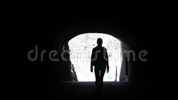 镜头跟随一个女人的剪影穿过黑暗的隧道走向空中举起的手臂视频的预览图