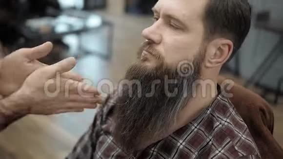 理发师的特写与一个长胡子的英俊男子做造型理发师在工作过程中手Barbe视频的预览图