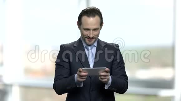 快乐的商人在他的智能手机上玩游戏视频的预览图