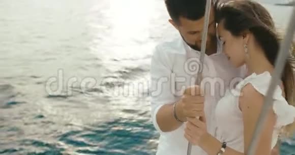 恋爱中的情侣在游艇上放松风吹着女人衣服而男人则站在白色游艇上拥抱她的温柔视频的预览图