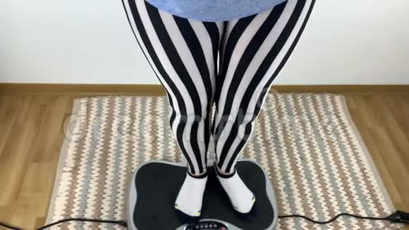 穿条纹紧身裤的女人在振动模拟器上进行体育锻炼运动减肥体能的概念视频的预览图