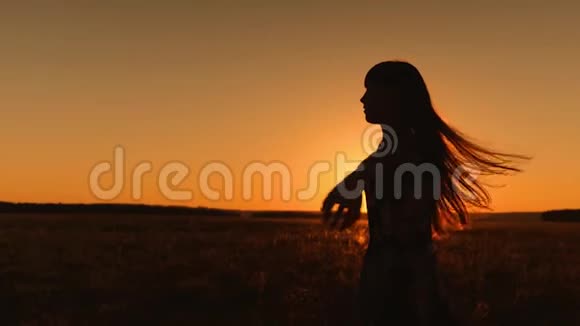 美丽的女孩留着长发在金色的阳光下跳舞和旋转慢动作视频的预览图