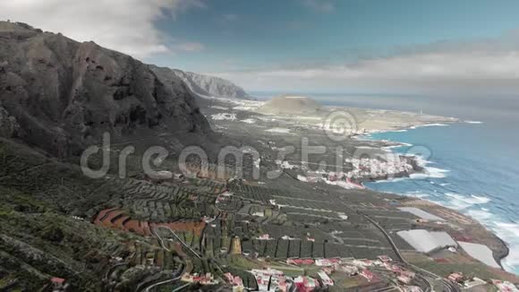 空中射击蓝色的海洋和火山海岸高山之路有蛇和发夹一个小镇的海岸视频的预览图