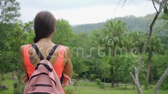 美丽的热带雨林带着一个年轻的女旅行者背着一个背包去泰国森林一个女人走过来视频的预览图