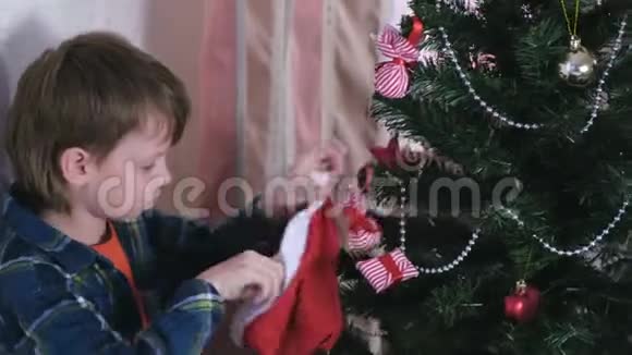 男孩从圣诞帽上拿圣诞装饰品装饰圣诞树视频的预览图