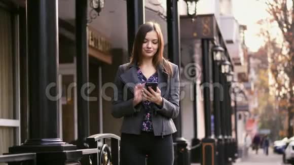漂亮的女商人在街上使用智能手机应用程序上网和微笑慢动作视频的预览图