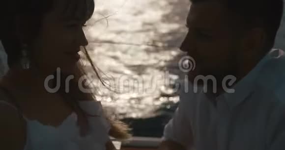 在游艇上恋爱的情侣男人亲吻女人手而她们坐在游艇上的夕阳下视频的预览图