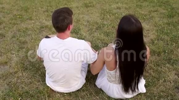 有趣的青少年情侣在夏天公园的草地上牵手视频的预览图