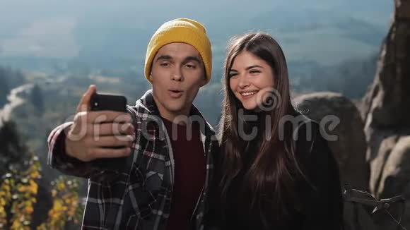恋爱中的年轻夫妇站在山上的一块岩石上和朋友视频聊天旅游交流视频的预览图