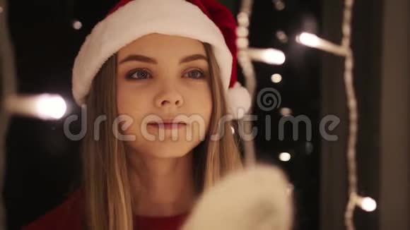 女人站在装饰有花环的窗户附近新年圣诞节视频的预览图