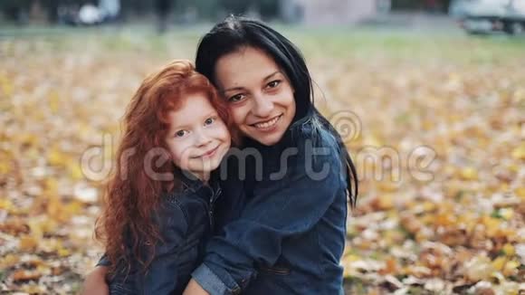 快乐的母亲和女儿看着站在秋天公园里的相机女孩们笑着笑着慢动作视频的预览图
