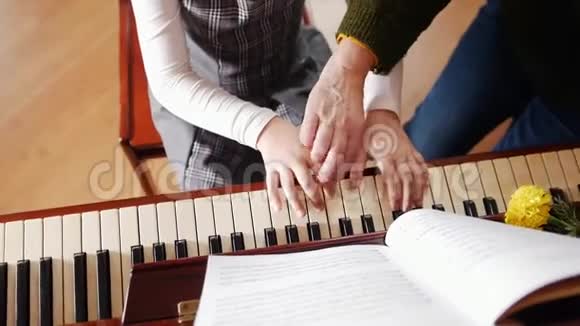 音乐课女孩弹钢琴年长的老师站在钢琴附近帮助演奏从顶部看视频的预览图