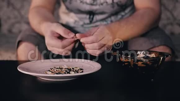 一个人吃杯中的种子把壳扔进盘子里快速录像回放视频的预览图