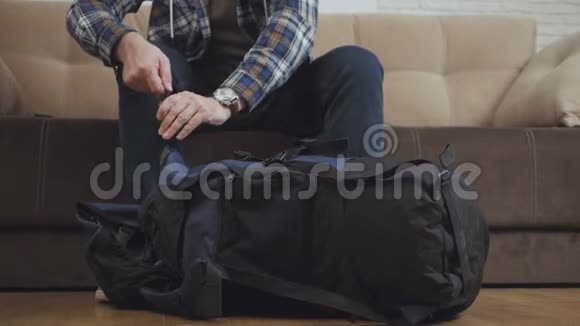 一个男人坐在沙发上把东西放在背包里把它系紧然后离开框架视频的预览图