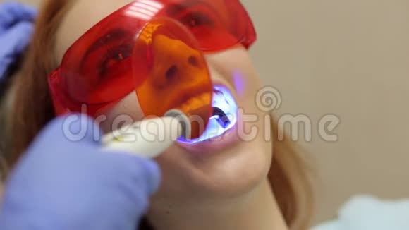 一个女孩的特写躺在安全眼镜的牙科椅上牙齿美白视频的预览图