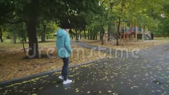 雨天在秋天公园散步的漂亮女孩视频的预览图