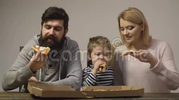 快乐的家人吃披萨妈妈爸爸和儿子一起吃披萨幸福的家庭观念视频的预览图