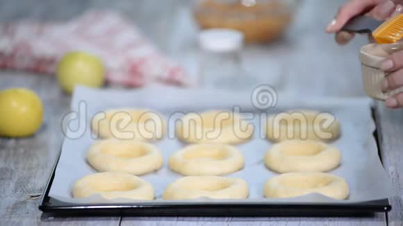 女人手用鸡蛋润滑面包用苹果Vatrushka煮开面包传统的俄罗斯烘焙系列视频的预览图