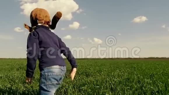这位穿着飞行员西装孩子沿着绿色的田野奔跑他的双手缓慢地在飞机上飞行视频的预览图