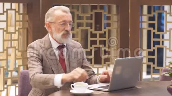 一个办公室概念的老商人在休息的时候带着笔记本电脑视频的预览图