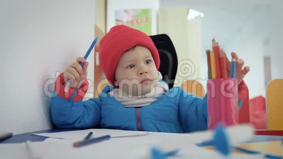 一个穿着游戏室衣服的小孩子在相册里画铅笔视频的预览图
