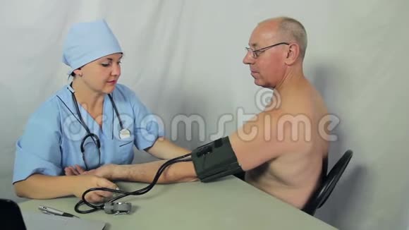 一位女医生坐着测量男性病人的压力照相机从左到右移动到小车上视频的预览图
