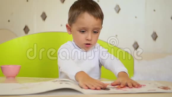 一个淘气的男孩拿颜料在纸上拍掌孩子的发展教育心理情感视频的预览图