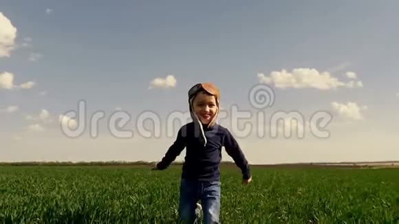 一个穿着飞行员西装孩子沿着绿色的田野奔跑他的双手缓慢地显示着飞机的飞行视频的预览图