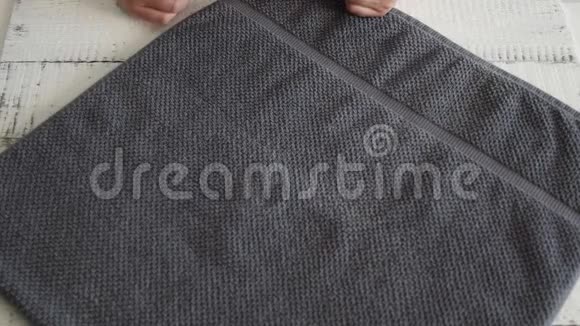 女人折叠一条灰色毛巾把它放在架子上视频的预览图
