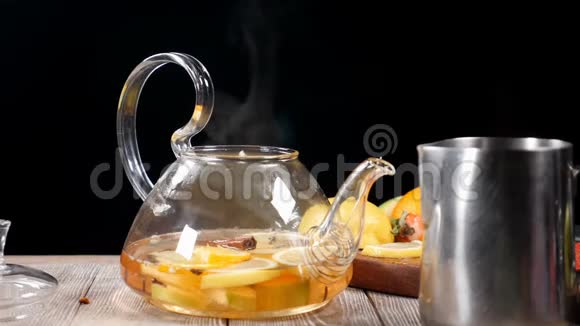 蒸汽从玻璃茶壶里出来里面有水果慢动作黑色背景茶道高清高清视频的预览图