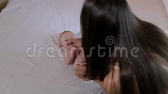 快乐妈妈亲吻她的小新生婴儿在肚子和脸颊特写视频的预览图