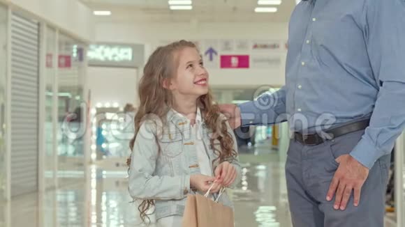 快乐的小女孩指着孩子们的商店和她的父亲在购物中心购物视频的预览图