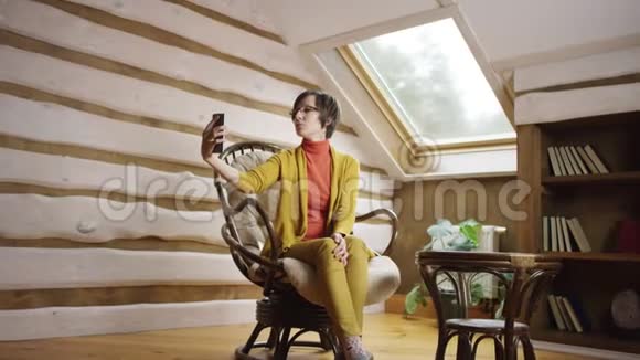 戴眼镜的美女在阁楼上的智能手机上拍照视频的预览图