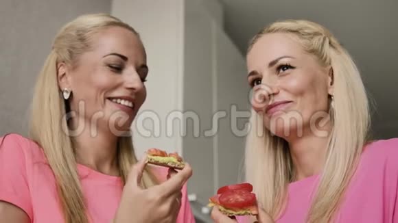 两个金发女郎吃一个红鱼三明治和一个西红柿烤面包视频的预览图
