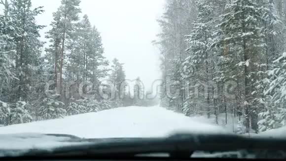 这辆车站在下雪的森林道路上视频的预览图