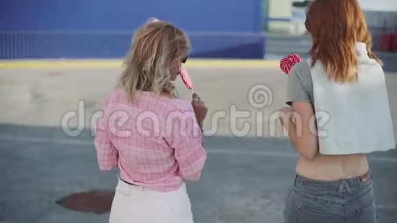 两个年轻漂亮的女人在街上散步聊天吃棒棒糖视频的预览图