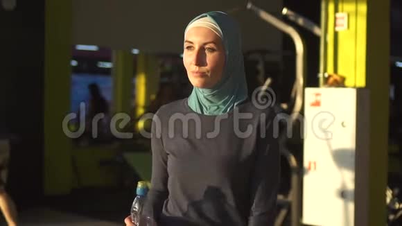 年轻的穆斯林运动女孩戴着头巾来到健身房trainingSunflareSlow莫视频的预览图